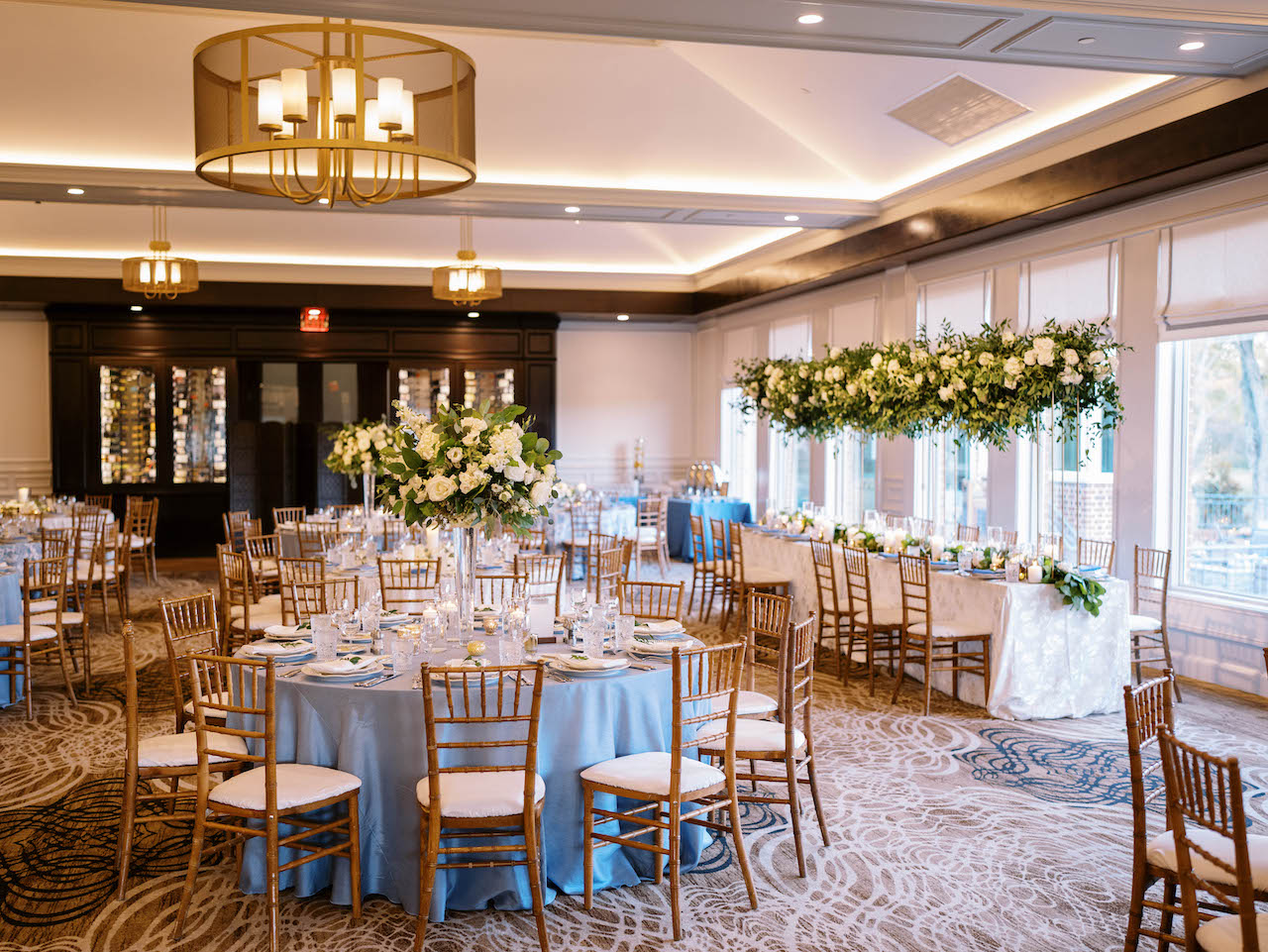 Elevated and low centerpieces in classic green and white alternate across ballroom for River Bend Country Club wedding